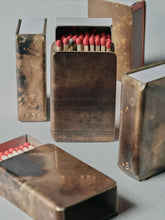 Multiple handmade brass matchbox holders by 13 Knives with Redheads matches, showing patina variations and striker detail