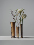 Set of three handcrafted brass vases by 13 Knives Melbourne Australia holding seasonal flowers on a minimal backdrop